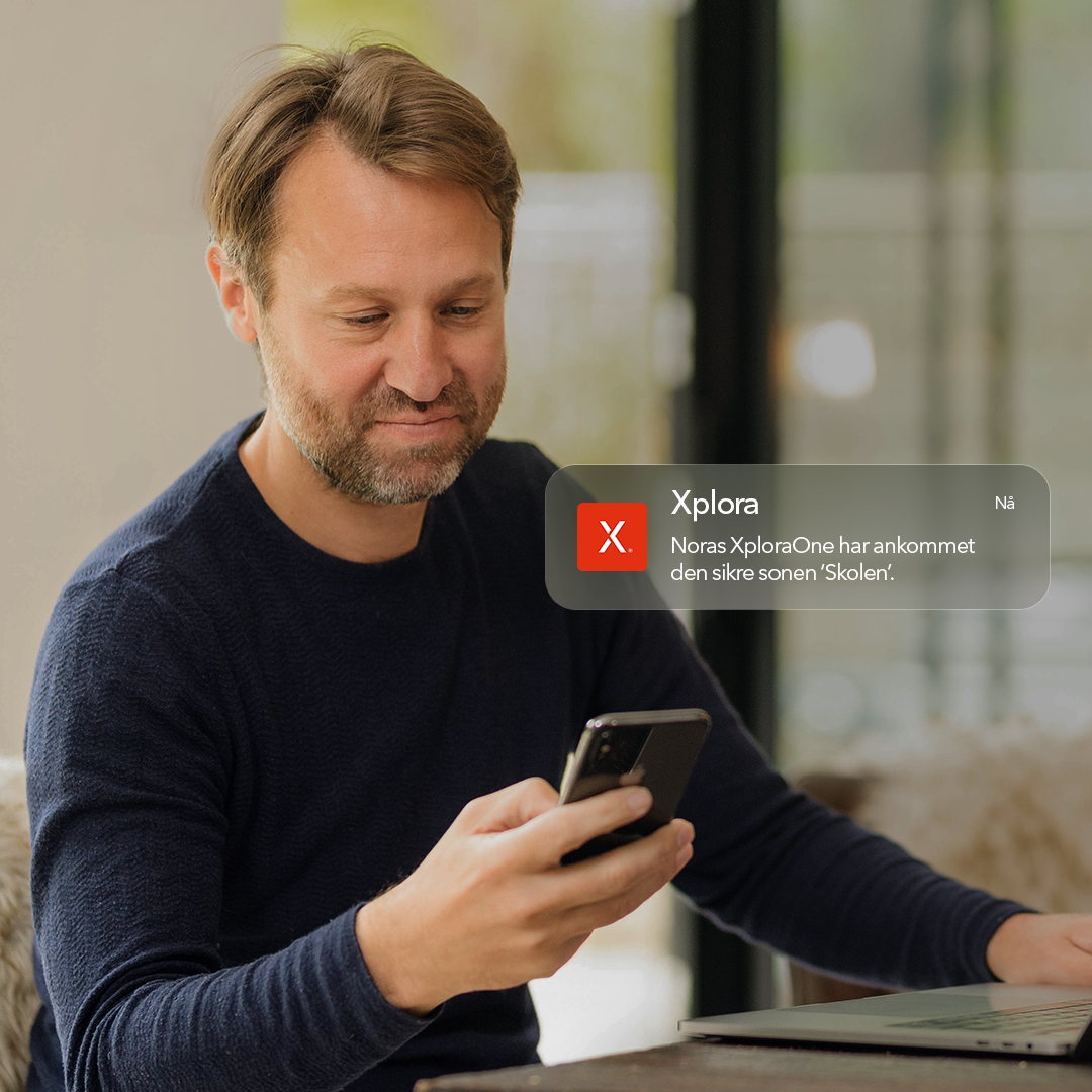 En forelder ser på mobilen hjemme med et Xplora-varsel om Skolemodus.